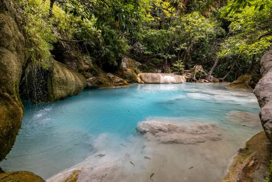 Air terjun dengan kolam alami di bawahnya, dikelilingi pepohonan hijau